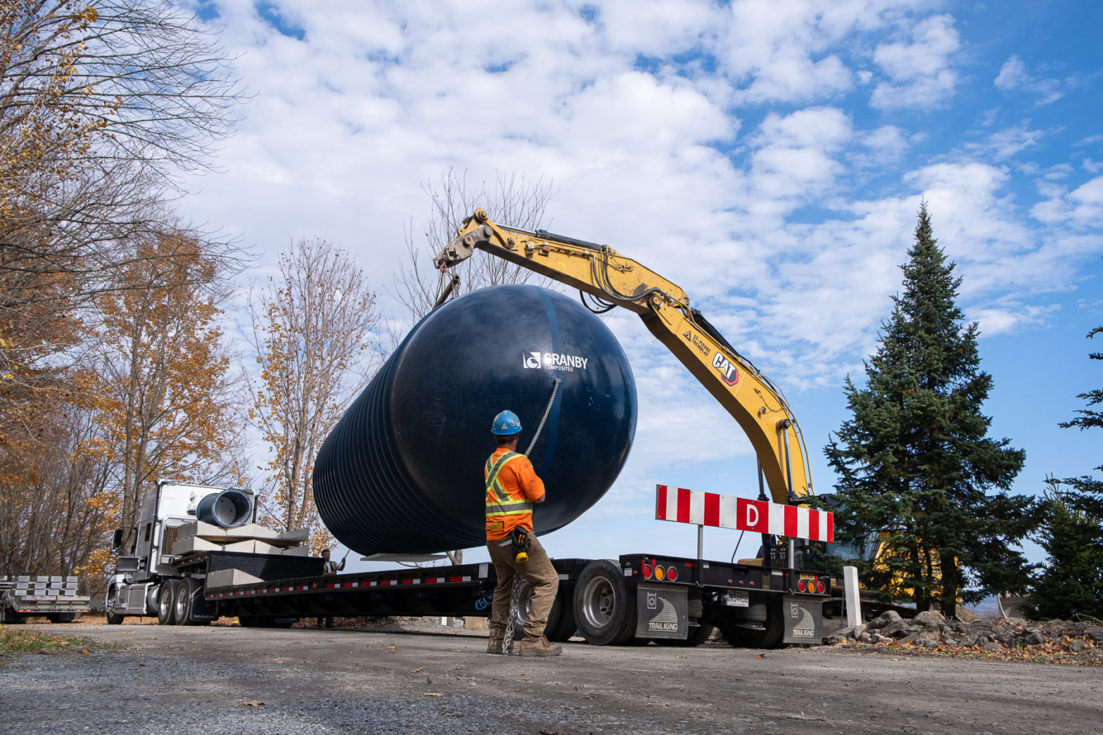 Crane loading a large industrial storage tank onto a flatbed trailer for delivery